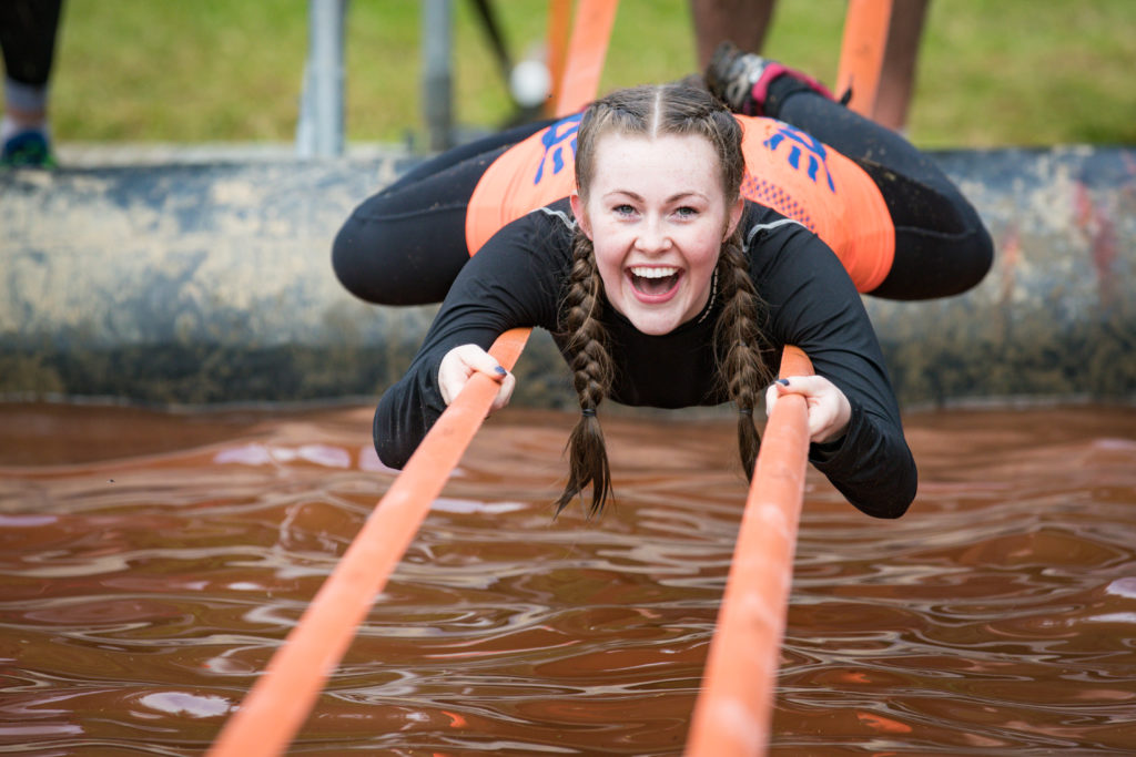 A woman lies across two straps smiling