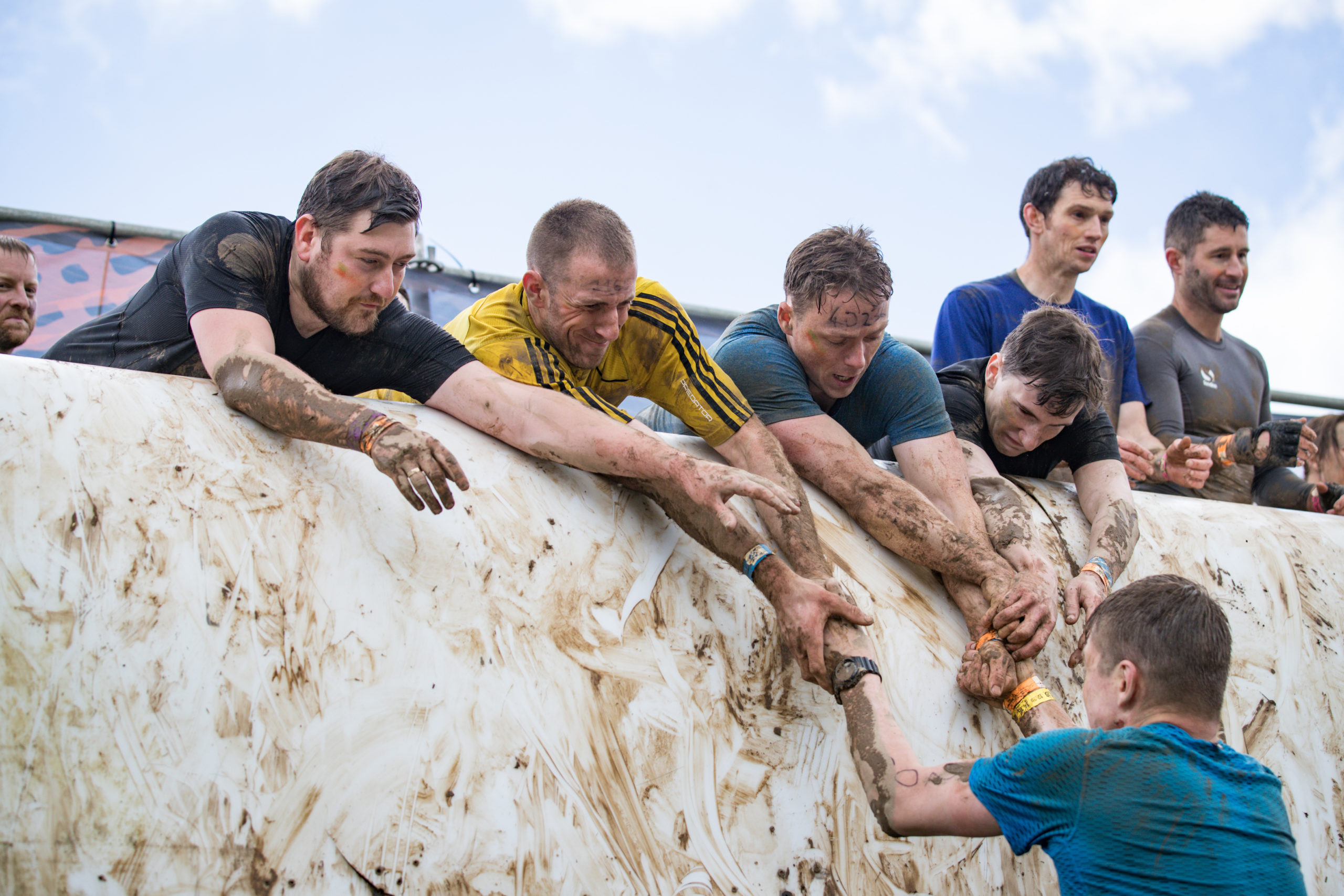 Participants lifting their teammate to reach the top