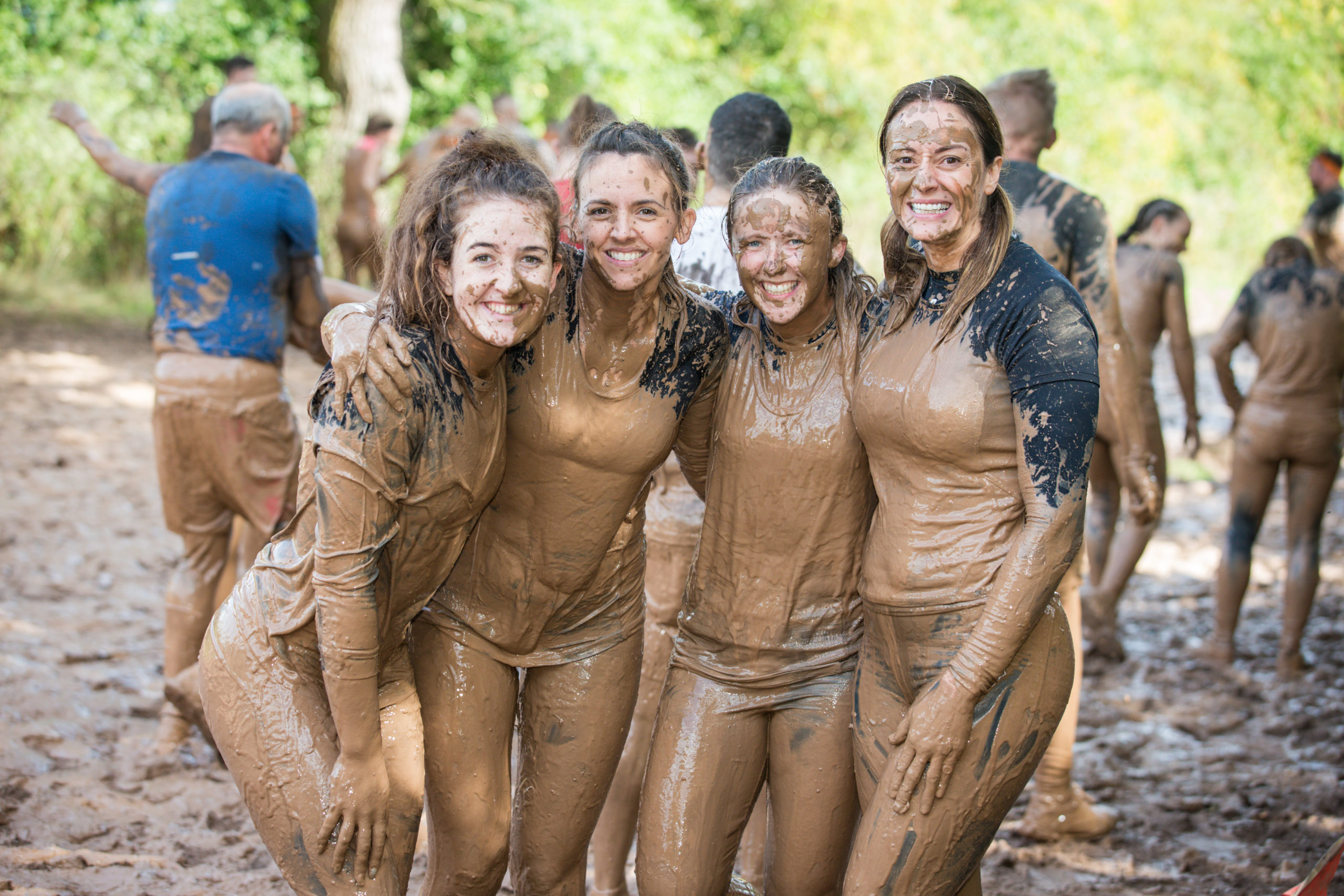 Four muddy women smiling