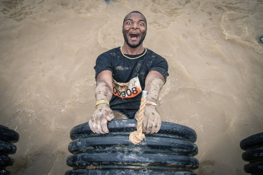 A man dangles from the end of a pipe grinning