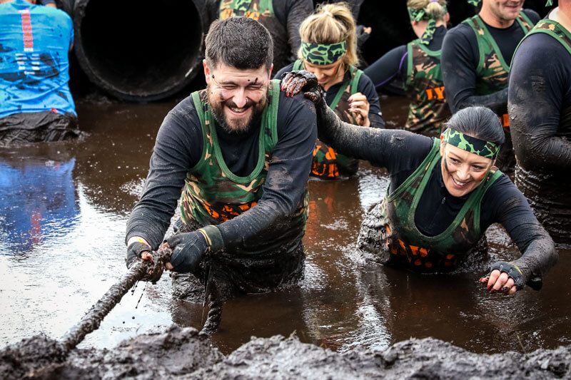 Participants trying to get out of the mud with the rope