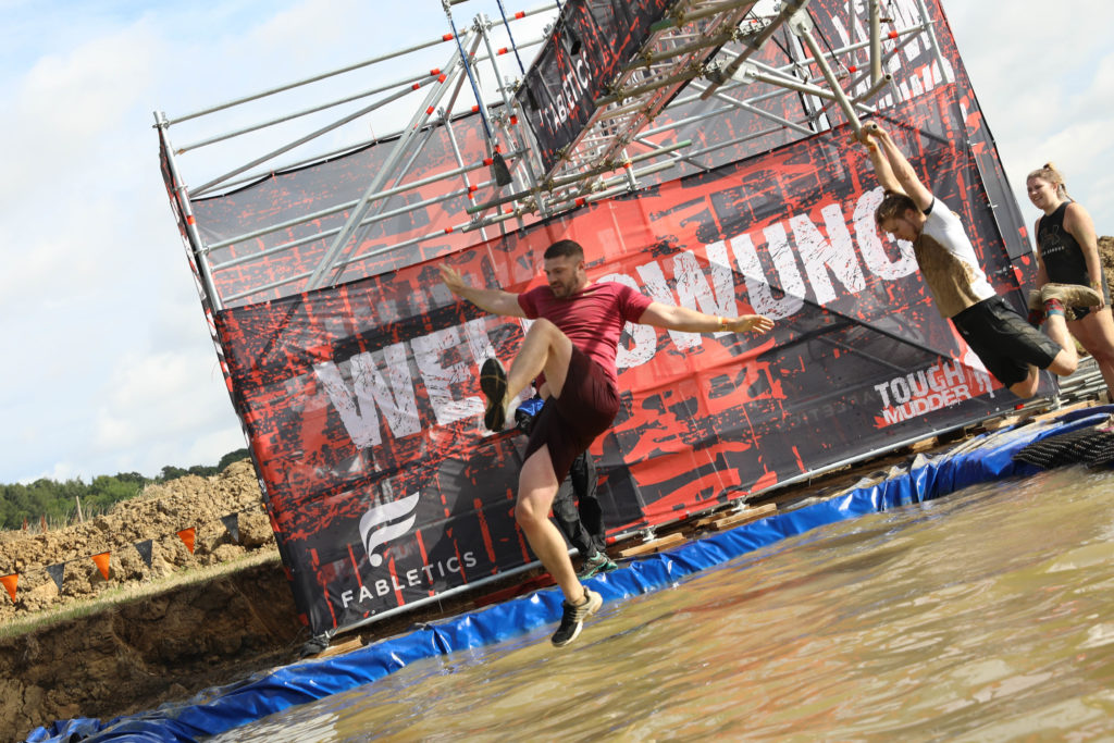 man swinging water obstacle