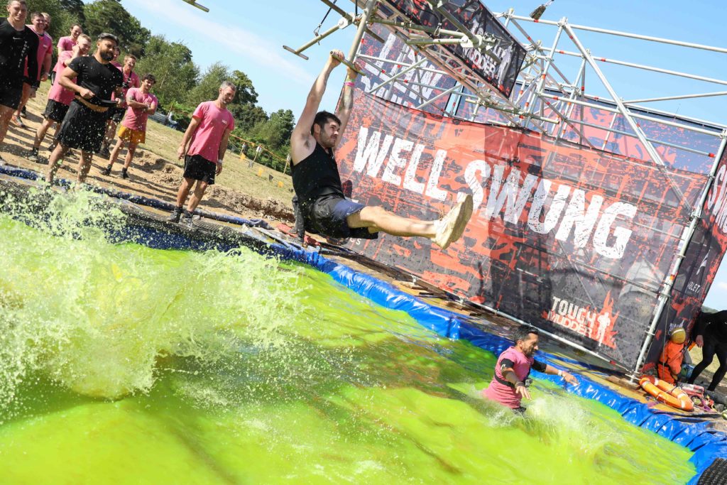 man swinging over green water