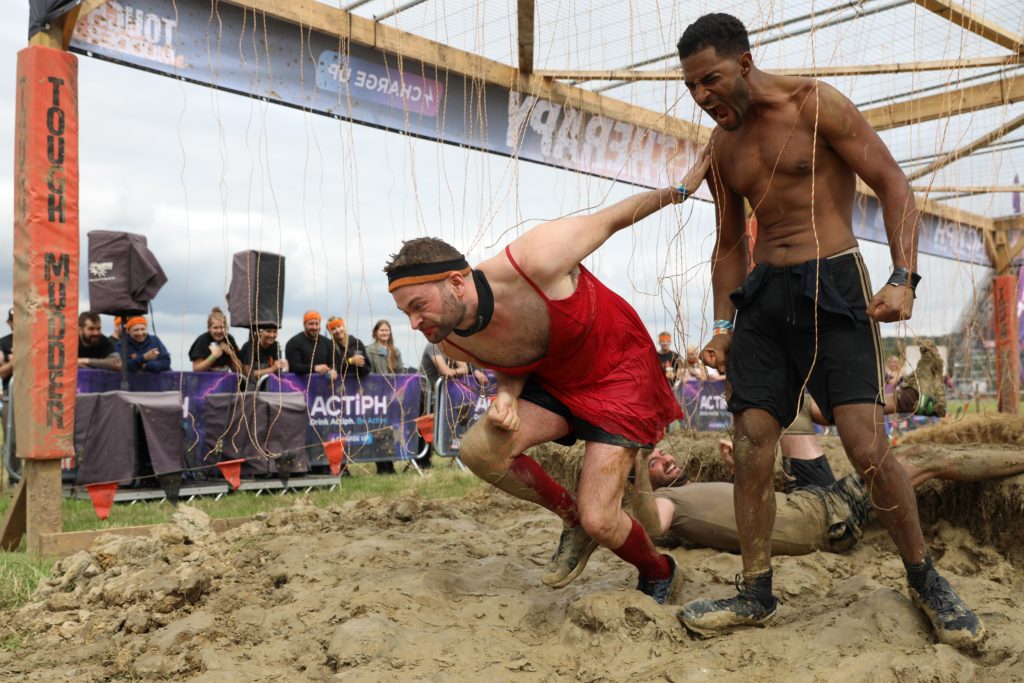 two men running through mud obstacle 