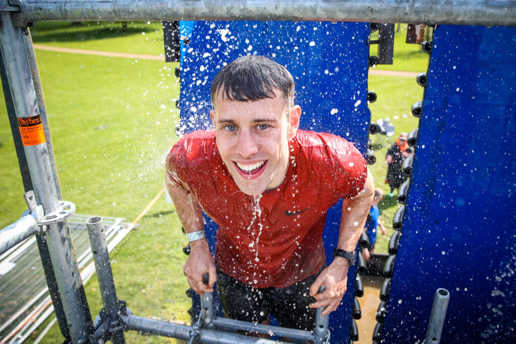 man climbing up water obstacle 
