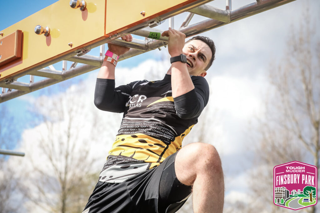 man on monkey bar like obstacle at event