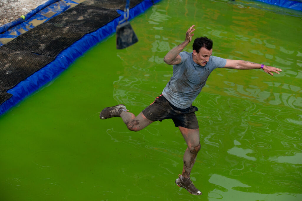 man flying in air after jumping onto Tough Mudedr obstacle