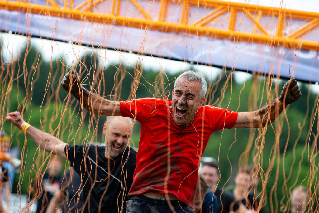 man cheering in middle of Tough Mudder obstacle