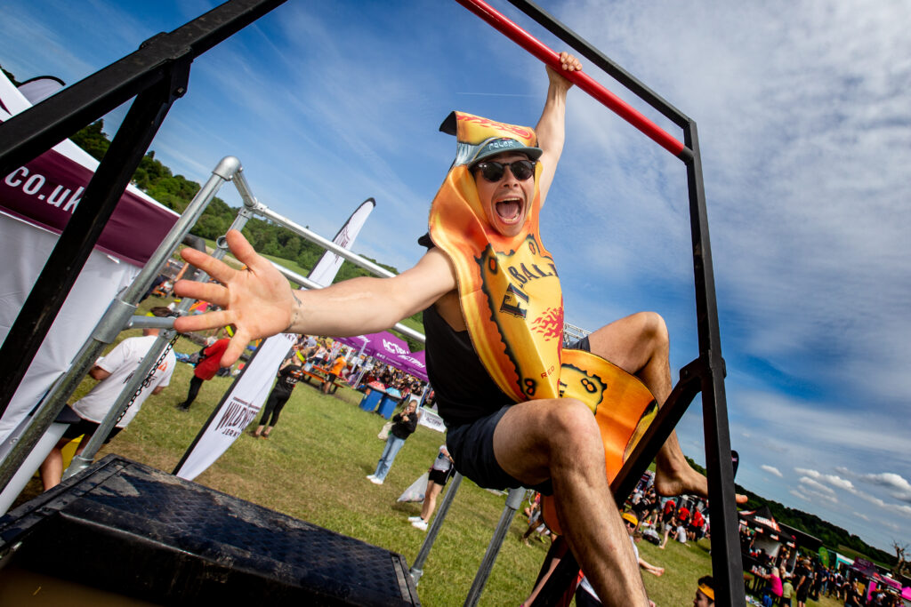 man swinging on bar in Fireball bottle costume
