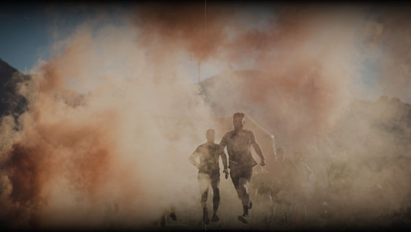 Tough Mudder participants running through orange smoke.