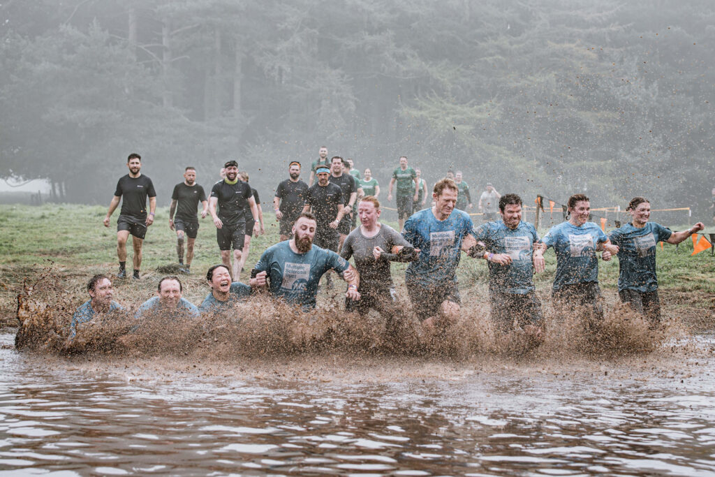 Participants linking arms while walking through the mud water