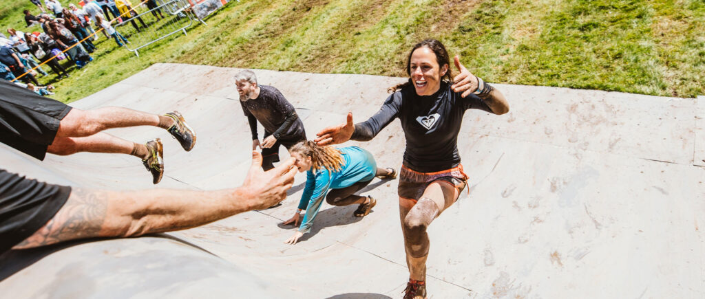 A participant reaching the hand of another participant at the top of the Everest